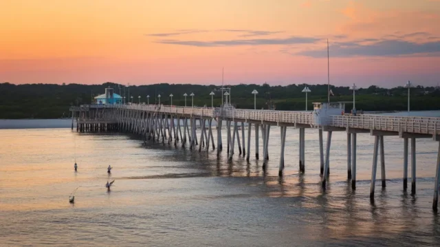 Fishermen casting fishing lines at Destin Pier during sunset, showcasing the scenic beauty and ideal fishing conditions.